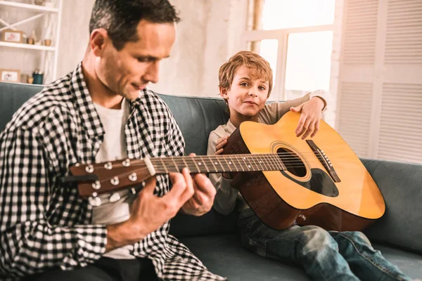 Pequeño niño sosteniendo una guitarra soñando con su futura carrera como músico . — Foto de Stock