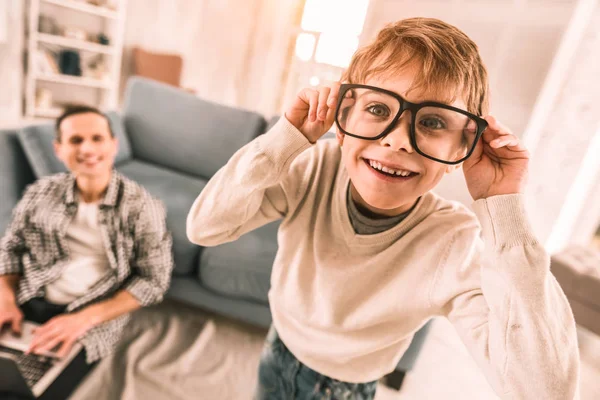 Piccolo ragazzo si diverte indossando i suoi padri occhiali da lettura . — Foto Stock