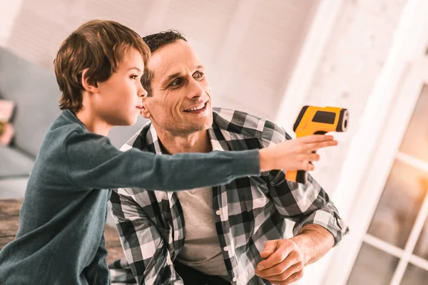 Loving responsible father and imaginative son playing spies with a glue gun.