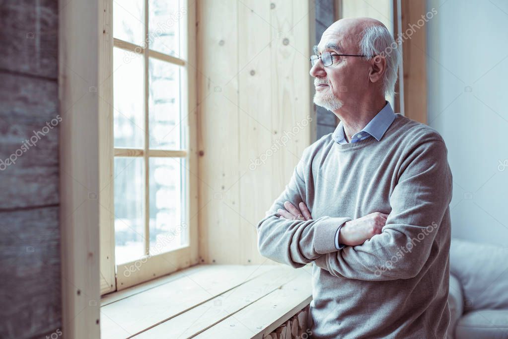 Thoughtful senior male person standing in semi position