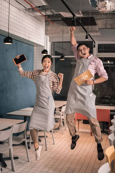 Casal pulando alto enquanto se sente incrível abertura negócio da família — Fotografia de Stock