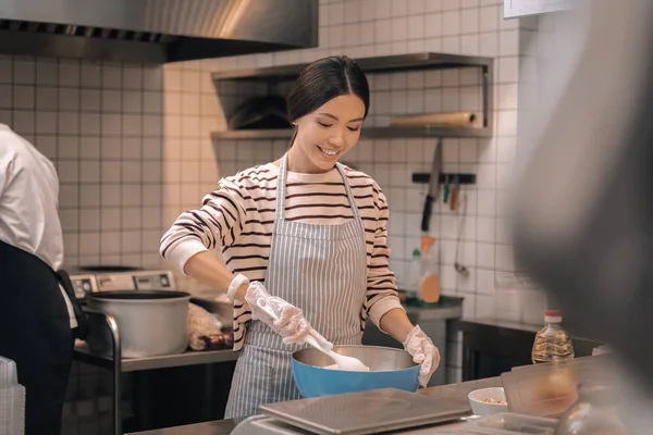 Корисний працівник ресторану, який допомагає шеф-кухареві готувати на кухні — стокове фото