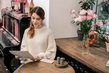 Kafede otururken bir menüyü okuyan kadın