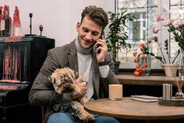 Bir telefon görüşmesi yaparken bir köpek tutan adam