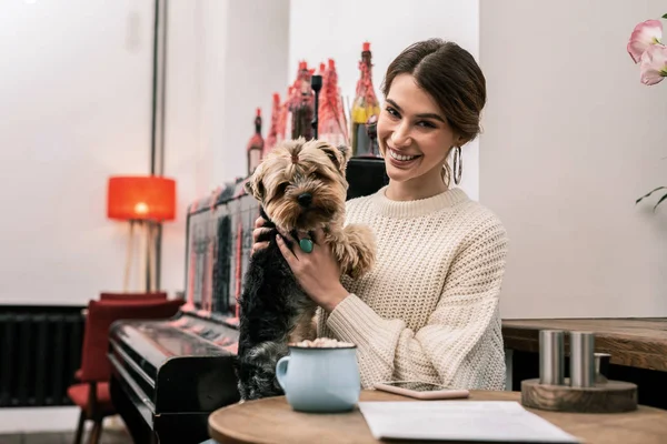 Улыбающаяся женщина приходит в кафе со своей собакой — стоковое фото
