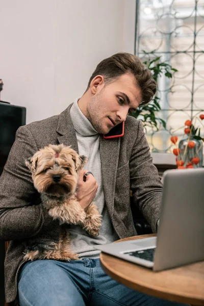 Busy man holding a dog while working