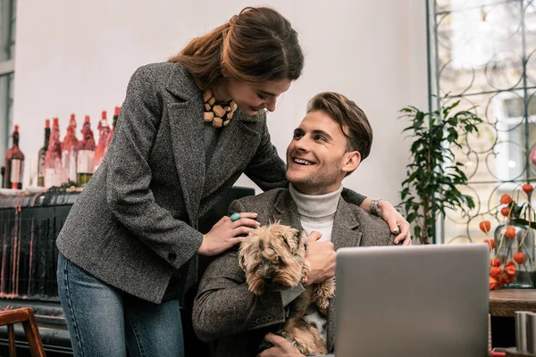 Woman hugging her boyfriend holding a dog — Stock Photo, Image