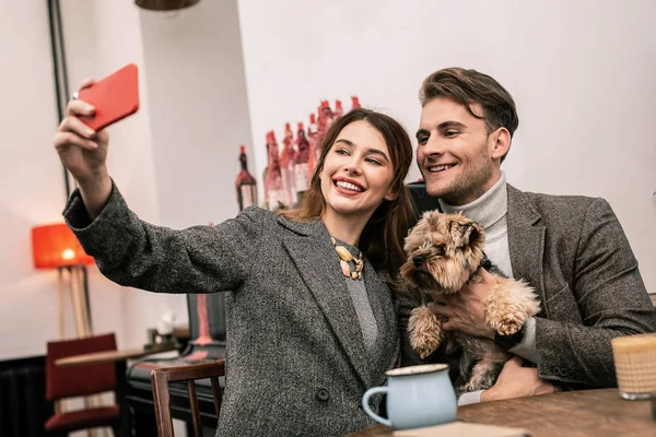 Smiling young family making selfie with their pet — Stock Photo, Image