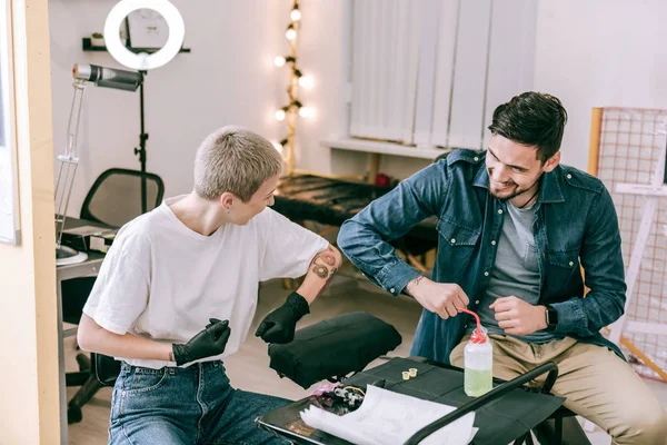 Female short-haired tattoo master and her male client having great time