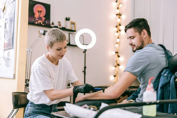Extraordinário mestre de tatuagem de cabelos curtos raspando o cabelo da mão — Fotografia de Stock