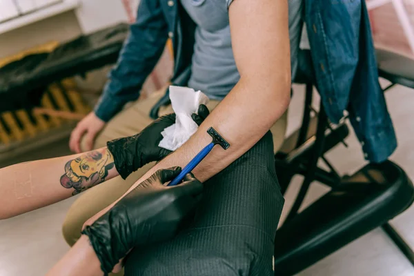 Tattoo master carrying disposable razor and using it for area