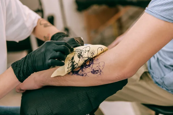 Внимательный мастер татуировки, открывающий макет бумаги из рук клиента — стоковое фото
