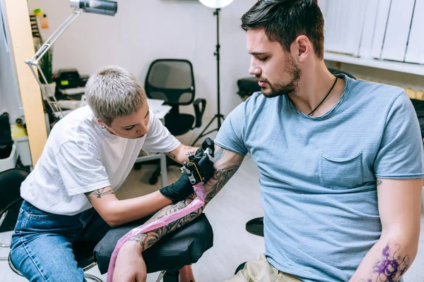 Loira artista de tatuagem de cabelos curtos trabalhando com tatuagem notável — Fotografia de Stock