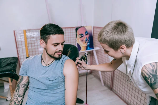 Profissional de boa aparência tatuagem artista pintura no ombro — Fotografia de Stock