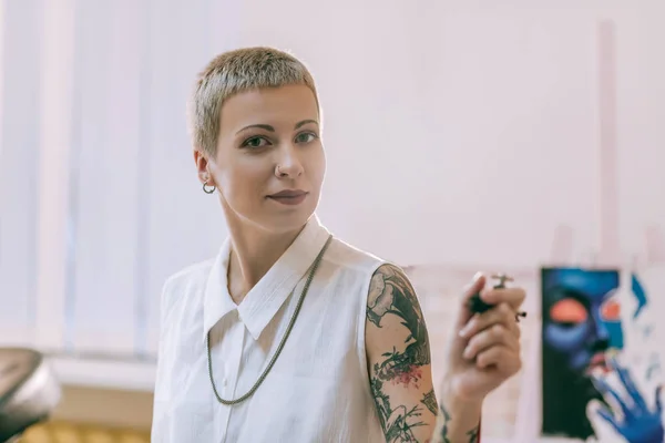 Leende kvinna med lugn makeup bär hennes tatueringsmaskin — Stockfoto