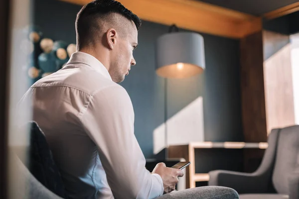 Joven pero próspero hombre de negocios sentado en su oficina usando el teléfono — Foto de Stock