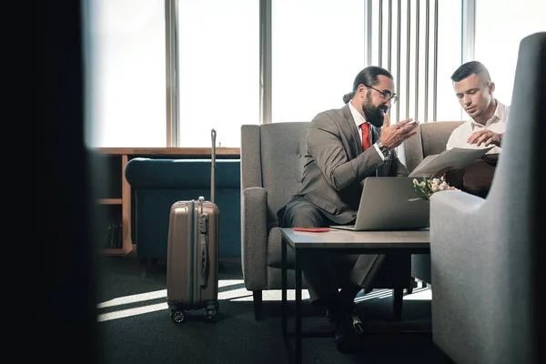 Dwóch partnerów biznesowych, siedząc na kanapie w holu hotelu w pobliżu ich bagażu — Zdjęcie stockowe