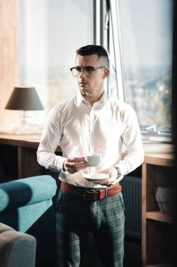 Şık genç ceo ayakta ofisinde kahve içme ferah ışık