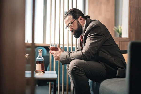 Otel lobisinde oturan ve viski içme Olgun deneyimli ekonomist — Stok fotoğraf