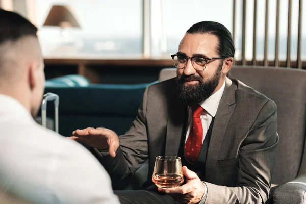 眼鏡をかけて彼のクライアントに話をしながらウイスキーを飲む弁護士 — ストック写真
