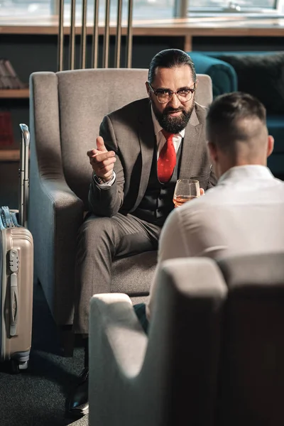 Бородатий чоловік сидить на кріслі біля багажу в готельному лобі — стокове фото