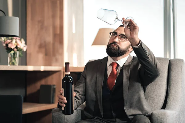 Hombre barbudo mirando un vaso vacío para tomar vino antes de beber — Foto de Stock