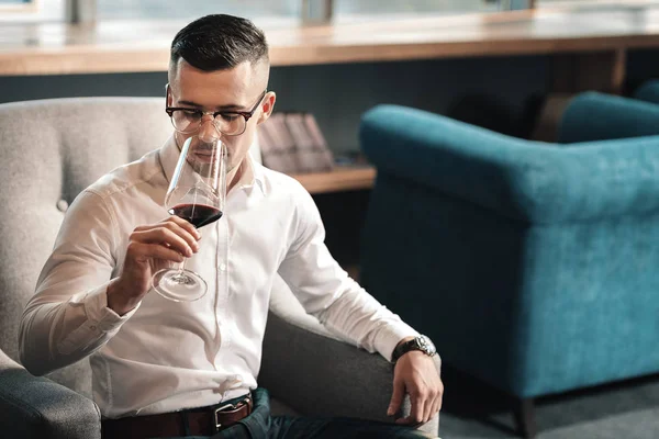 Knappe jonge man probeert rode wijn na lange vermoeiende dag — Stockfoto