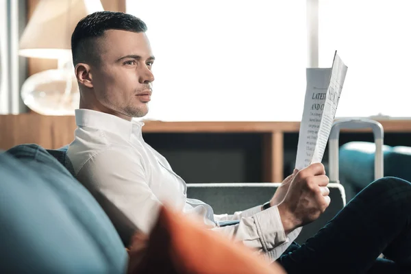 Bonito homem de cabelos escuros vestindo camisa branca segurando jornal — Fotografia de Stock