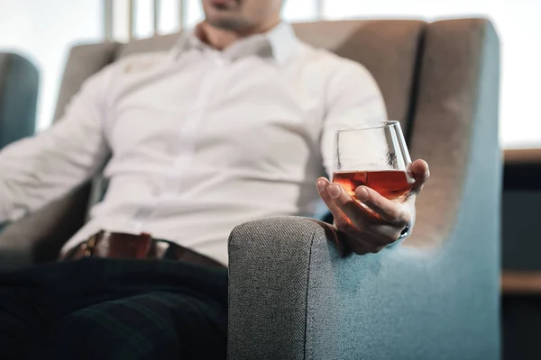 Крупный план человека в квадратных брюках, пьющего стакан виски — стоковое фото