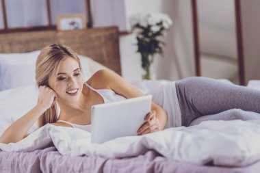 Yatakta yatarken ve video izlerken genç ve güzel kadın