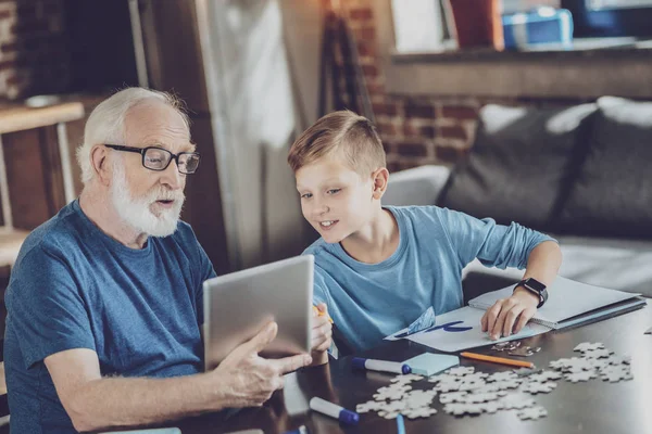 Attentive boy looking at tablet of his granddad — Stock Photo, Image