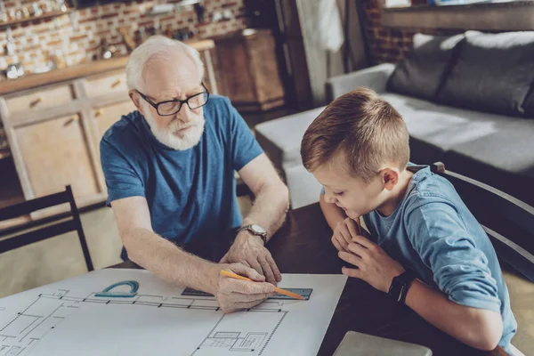 Attentive pupil looking at his granddads drawing — Stock Photo, Image