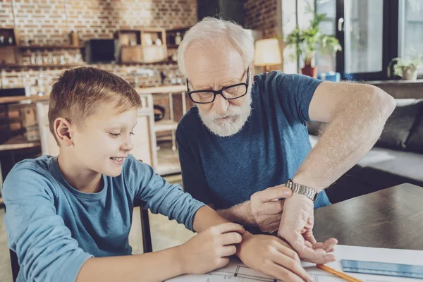 Attentive mature man pointing at his watches — Stock Photo, Image