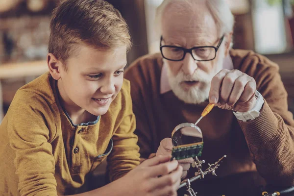 Concentrated retirement showing details to his grandson — Stock Photo, Image