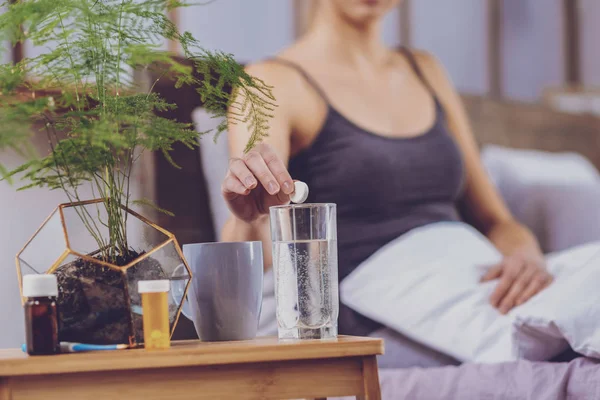 Mooie jonge vrouw die van glas met oplosbare geneeskunde — Stockfoto