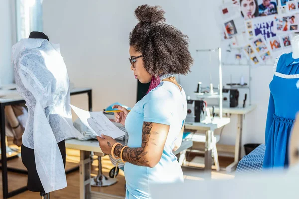 Short-haired extremely curly lady observing her drawing