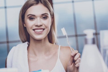 Bir diş fırçası tutan olumlu genç kadın