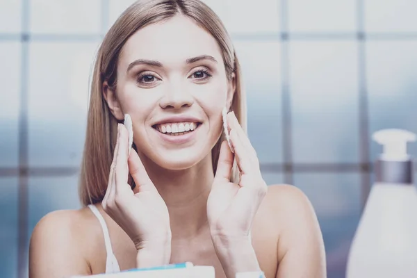 Mujer joven positiva limpiando su cara — Foto de Stock