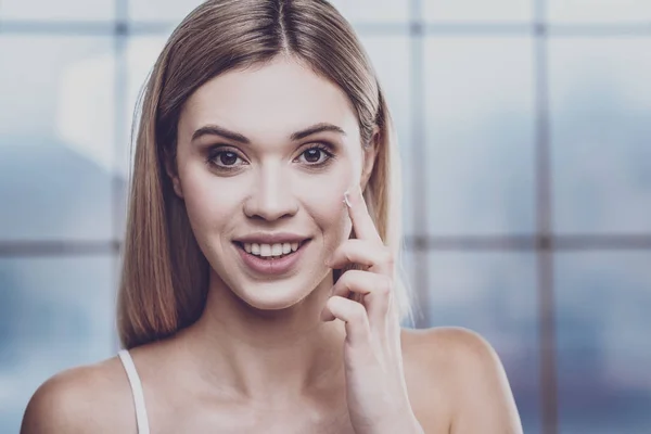 Mujer joven hidratando su cara con crema — Foto de Stock