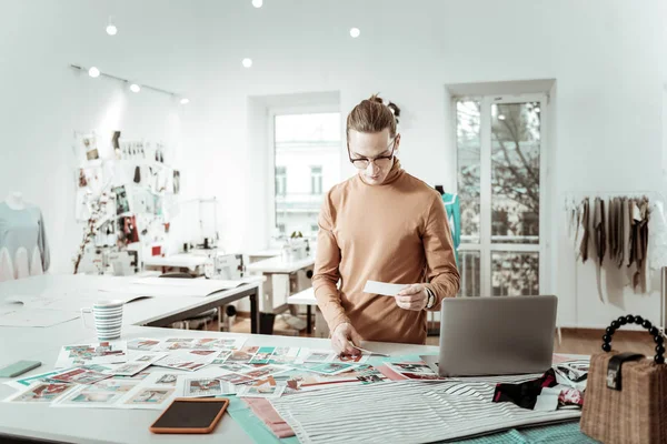 Long-haired designer in eyeglasses choosing concept for models