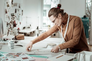 Ölçümler yaparak kahverengi bir giysi moda stüdyoda uzun saçlı Genç tasarımcı