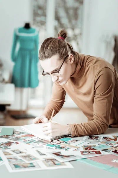 Attractive young fair-haired designer from generation Y making notes