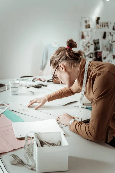 Guapo joven diseñador de una escuela de moda en gafas que trabajan con bocetos — Foto de Stock