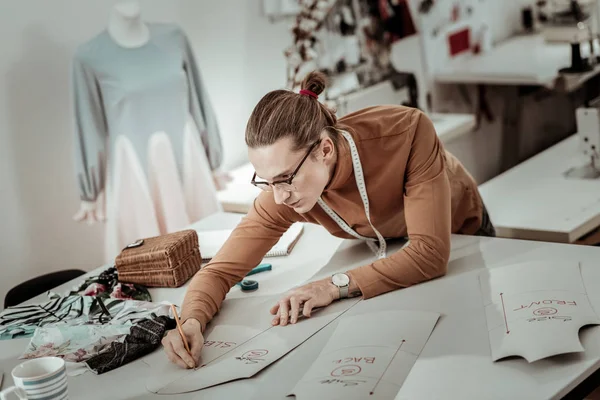 Молодой дизайнер в очках с длинными волосами работает над новой моделью одежды — стоковое фото