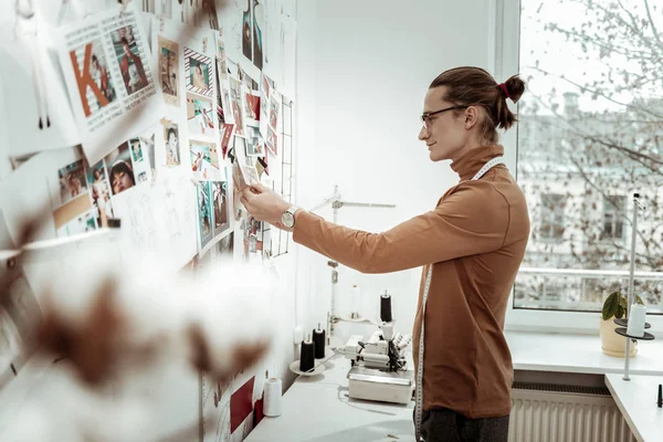 Jonge mode naaister in een bruin kledingstuk glimlachend positief — Stockfoto