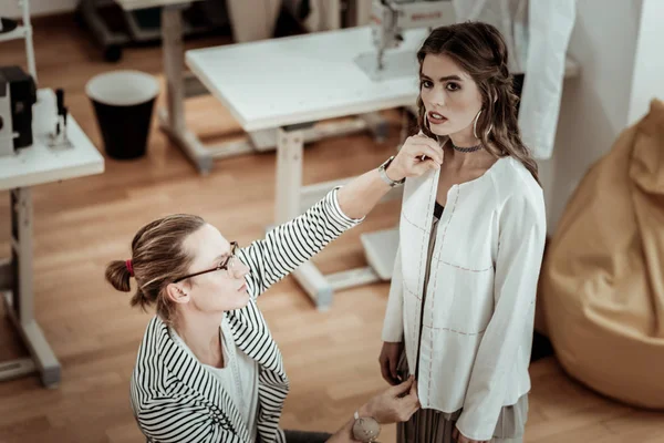 Modelo bastante moreno con grandes pendientes trabajando con un diseñador — Foto de Stock