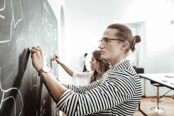 Przystojny młody krawieckie w okulary i piękny model patrząc skoncentrowany — Zdjęcie stockowe