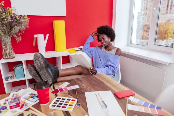 Fashion designer lägger benen på bordet medan du tittar på skisser — Stockfoto