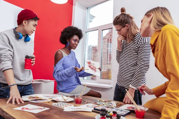 Três jovens artistas olhando para o trabalho de seu colega criativo — Fotografia de Stock