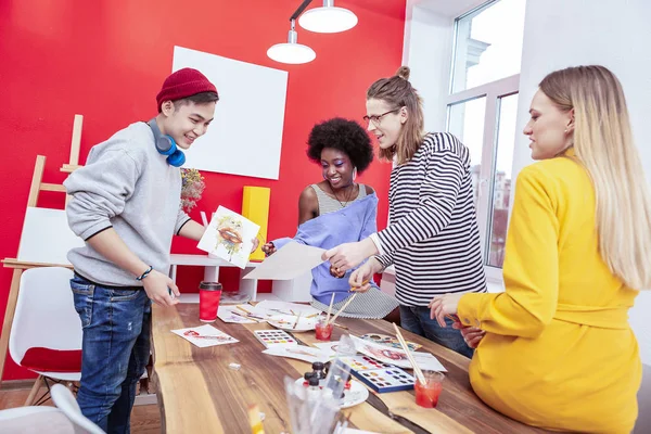 Quattro giovani artisti che hanno ispirazione lavorando in una bella camera spaziosa — Foto Stock